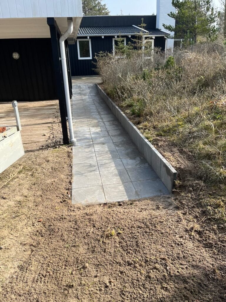 Ny flisebelagt sti langs sort hus