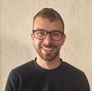 Smilende mand med briller foran lys væg