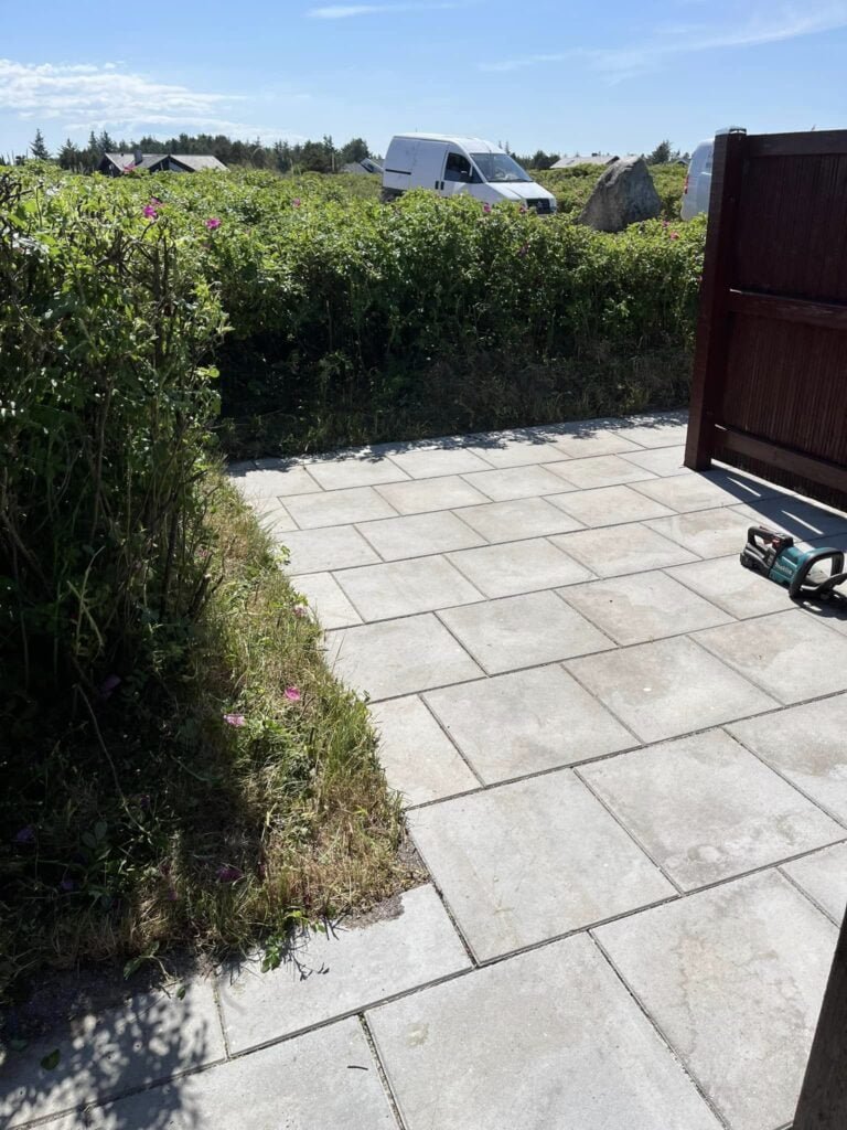 Nyfliseret terrasse med hæk og solrigt vejr