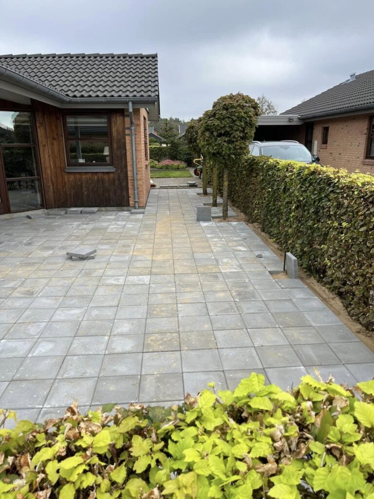 Nybelagt indkørsel med fliser og hæk