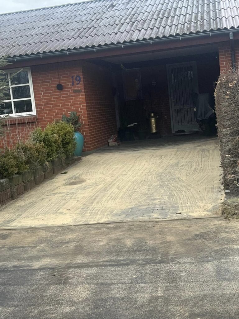 Murstenshus med carport og indkørsel i sand