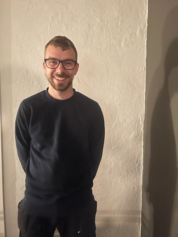 Smilende person med briller mod lys væg