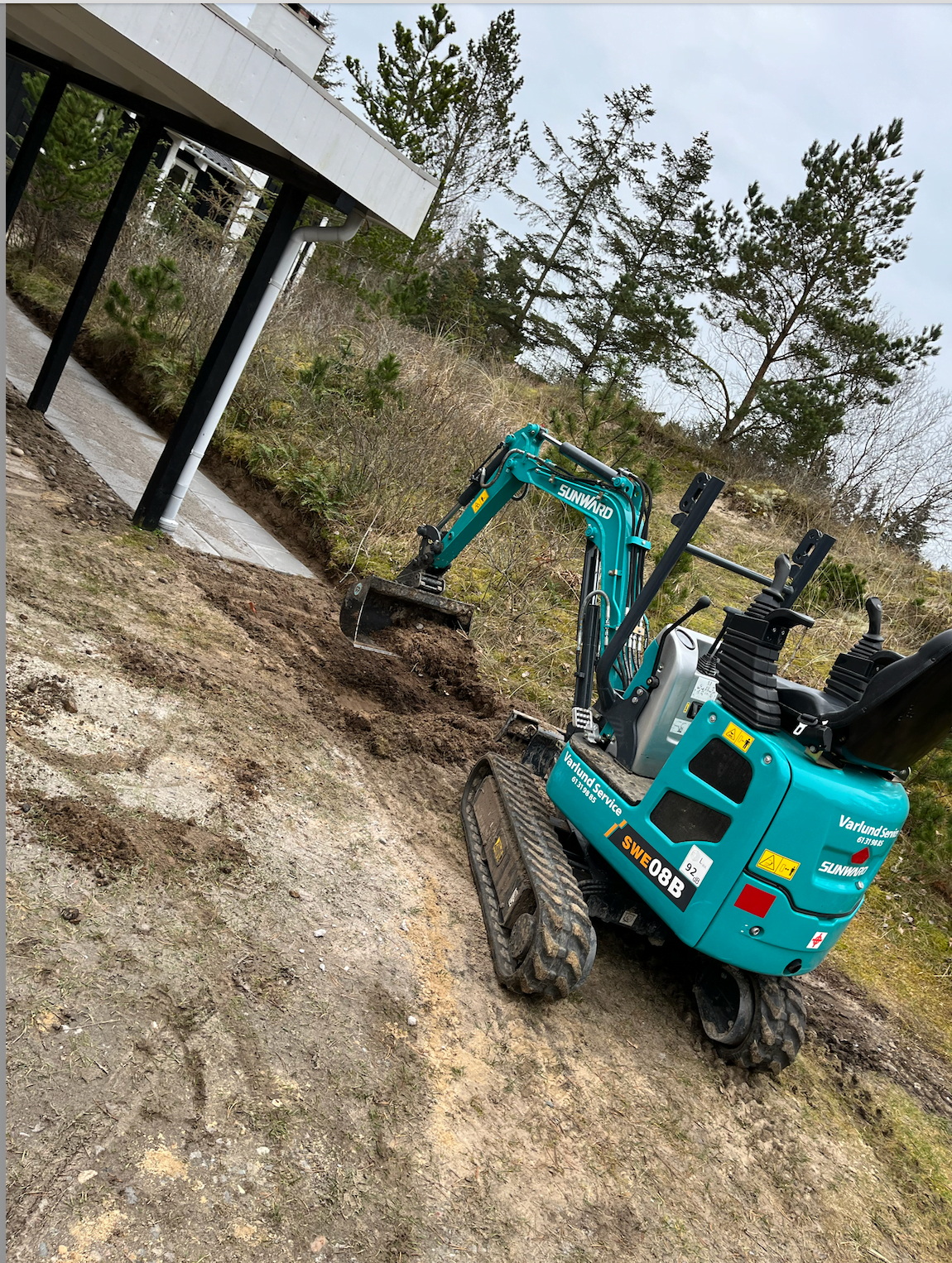 Gravemaskine arbejder ved hus i natur omgivelser